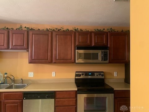 kitchen with appliances with stainless steel finishes, sink, and a textured ceiling