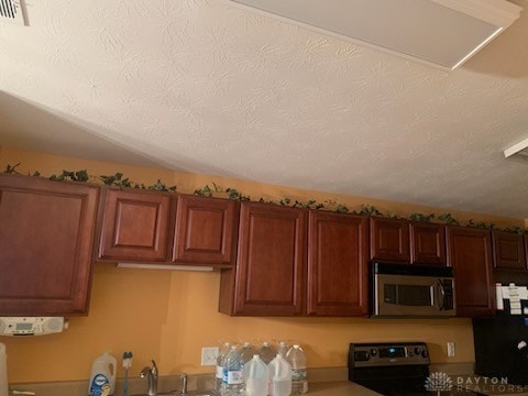 kitchen with a textured ceiling, fridge, and range with electric stovetop