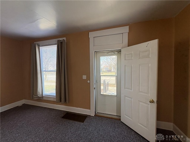 entryway featuring baseboards and dark colored carpet