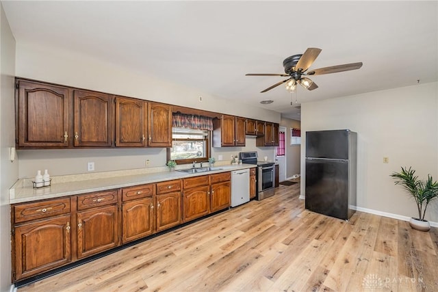 kitchen with light countertops, freestanding refrigerator, a sink, dishwasher, and stainless steel electric range