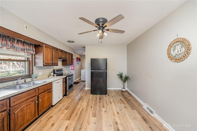 kitchen featuring light countertops, freestanding refrigerator, a sink, white dishwasher, and stainless steel electric range