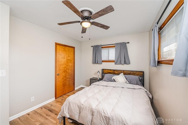 bedroom featuring light wood finished floors, baseboards, and a ceiling fan