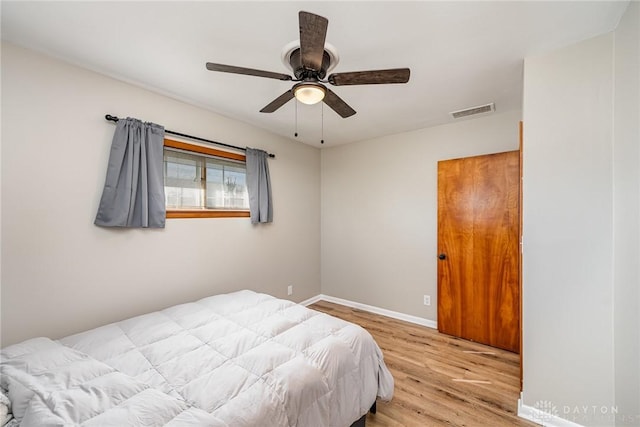 bedroom with light wood-style floors, baseboards, visible vents, and ceiling fan