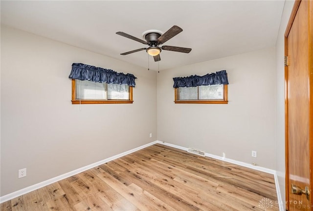 empty room with a ceiling fan, visible vents, light wood-style flooring, and baseboards