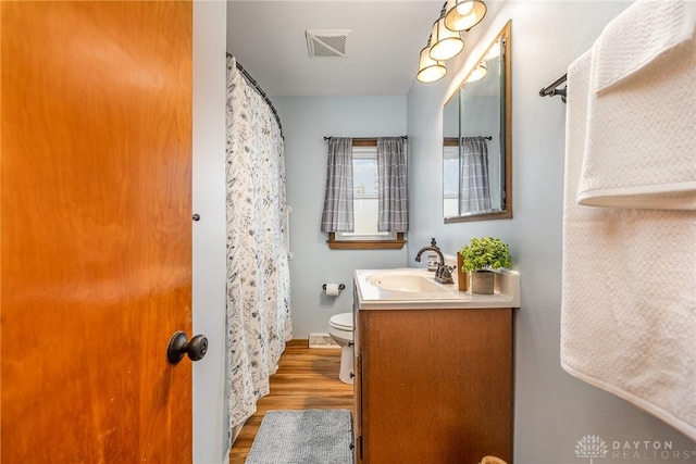 bathroom with visible vents, toilet, wood finished floors, and vanity