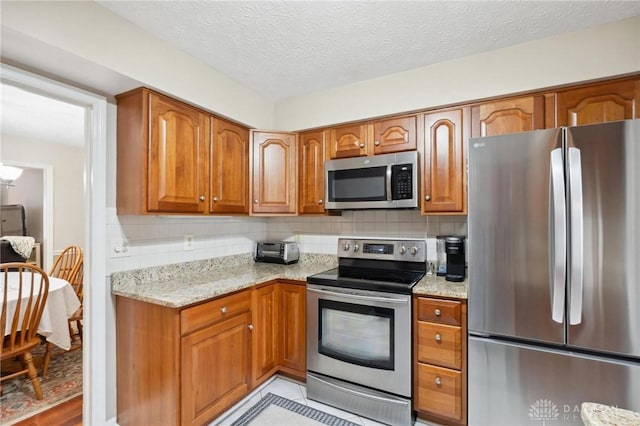 7789 Thomas Jefferson Ln, Centerville, OH 45459 - kitchen featuring appliances with stainless steel finishes, brown cabinets, light stone countertops, and tasteful backsplash