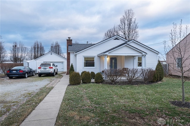 view of front of house with an outbuilding, a garage, a front yard, and covered porch