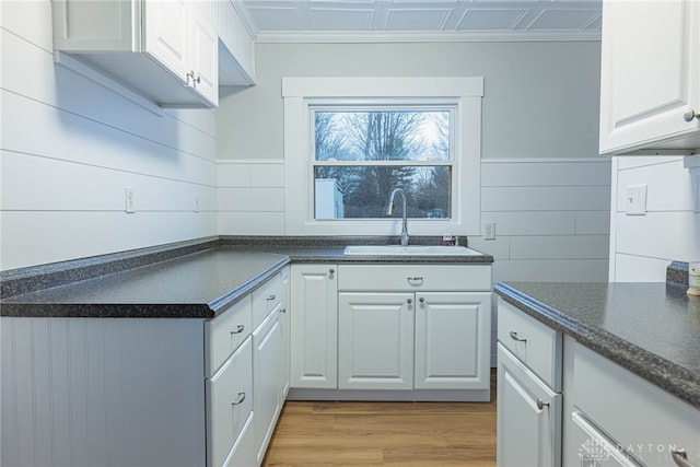 kitchen with sink, white cabinets, and light wood-type flooring