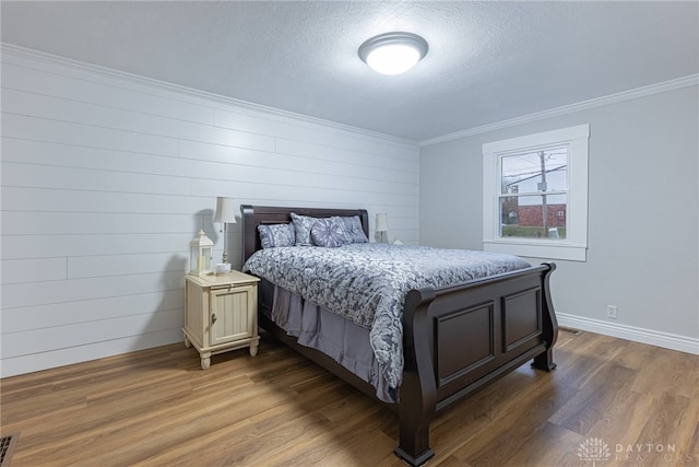 bedroom with crown molding, dark hardwood / wood-style floors, and a textured ceiling