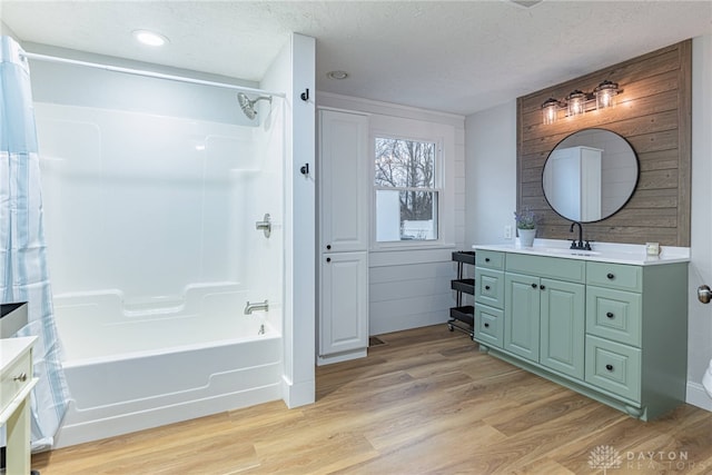 bathroom featuring hardwood / wood-style flooring, vanity, tub / shower combination, and a textured ceiling