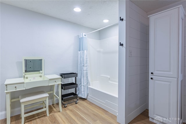 bathroom featuring shower / bathtub combination with curtain, hardwood / wood-style floors, and a textured ceiling