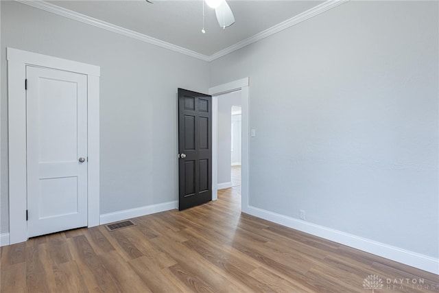 empty room with hardwood / wood-style floors and crown molding