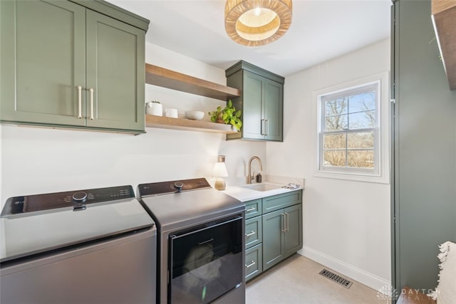 laundry area featuring washer and dryer, cabinet space, a sink, baseboards, and visible vents