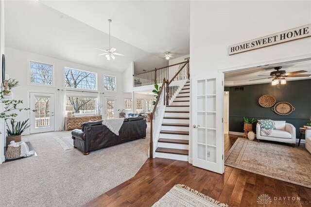 living room featuring ceiling fan, wood finished floors, stairway, and high vaulted ceiling