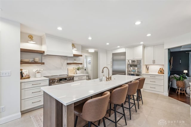kitchen with open shelves, custom exhaust hood, a kitchen bar, high quality appliances, and a sink