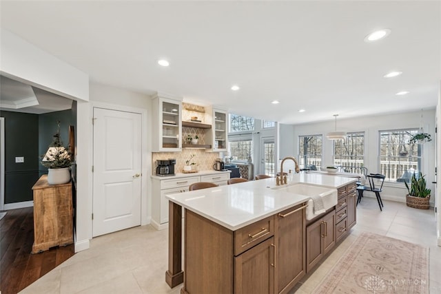 kitchen with open shelves, a sink, light countertops, glass insert cabinets, and recessed lighting