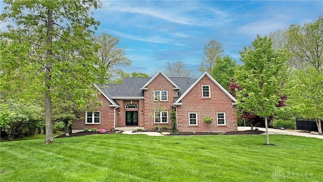 traditional-style home featuring french doors, brick siding, and a front yard