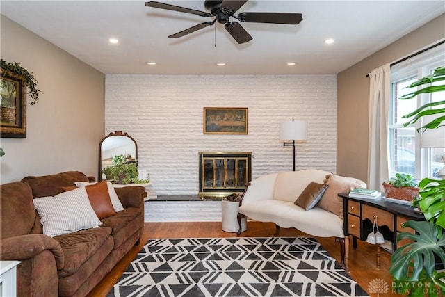 living room with ceiling fan, a fireplace, and wood-type flooring