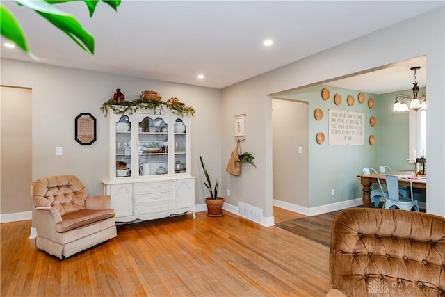 living area with an inviting chandelier and hardwood / wood-style flooring