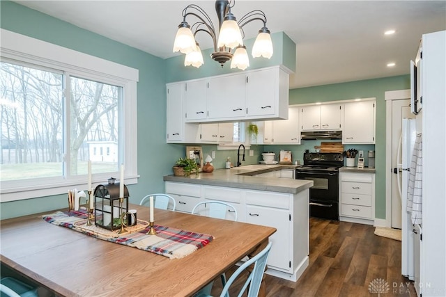 kitchen featuring electric range, kitchen peninsula, a wealth of natural light, pendant lighting, and white cabinets