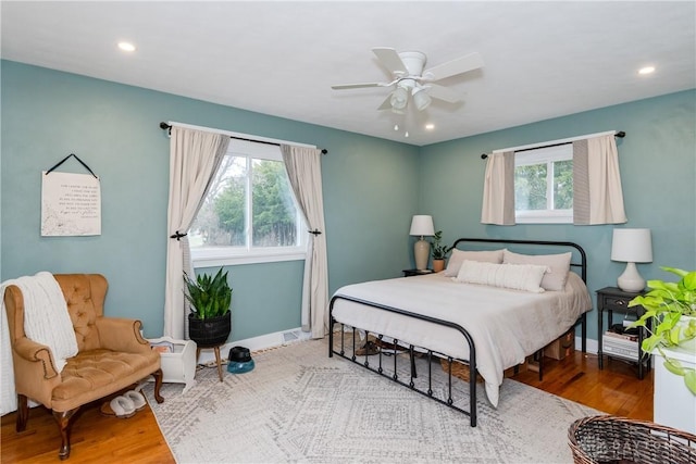 bedroom featuring hardwood / wood-style flooring, ceiling fan, and multiple windows