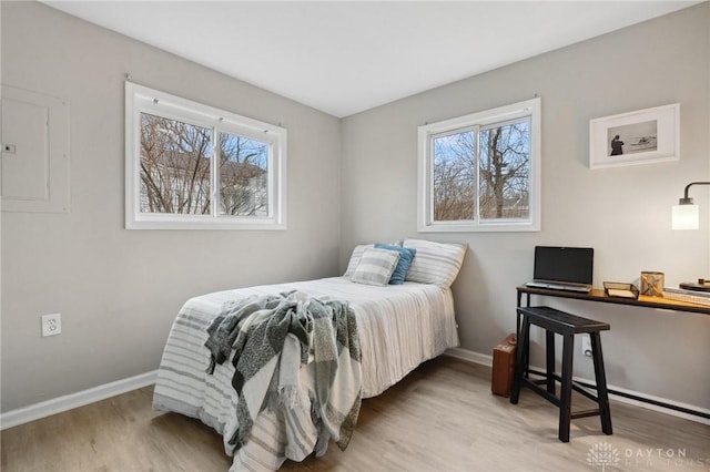 bedroom featuring multiple windows, wood-type flooring, and electric panel