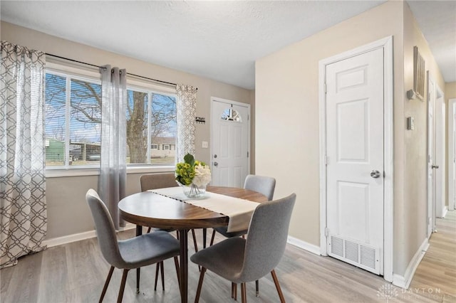 dining room featuring a textured ceiling and light hardwood / wood-style floors