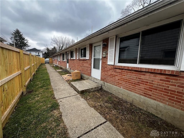 view of side of property featuring brick siding and fence