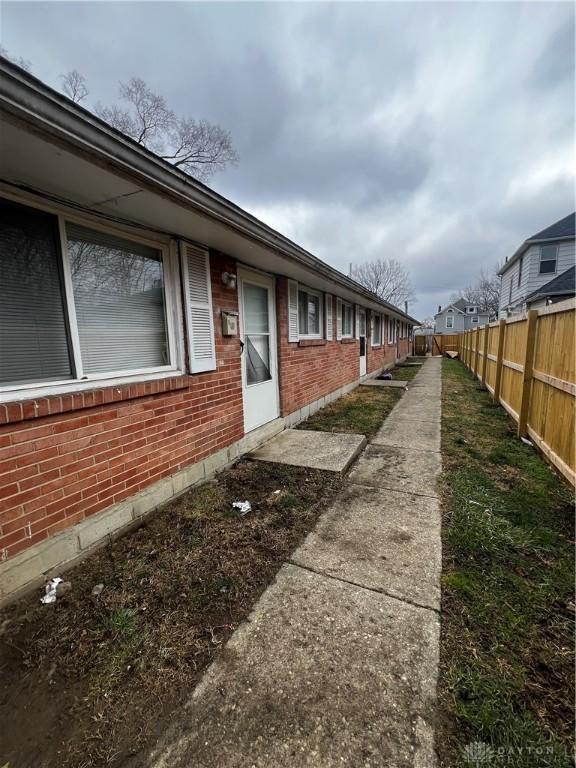 view of side of property featuring brick siding and fence