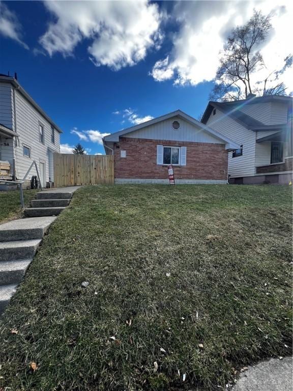 view of home's exterior with a lawn, brick siding, and fence