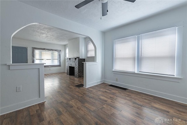 unfurnished living room featuring ceiling fan, dark wood-type flooring, a fireplace, and a textured ceiling