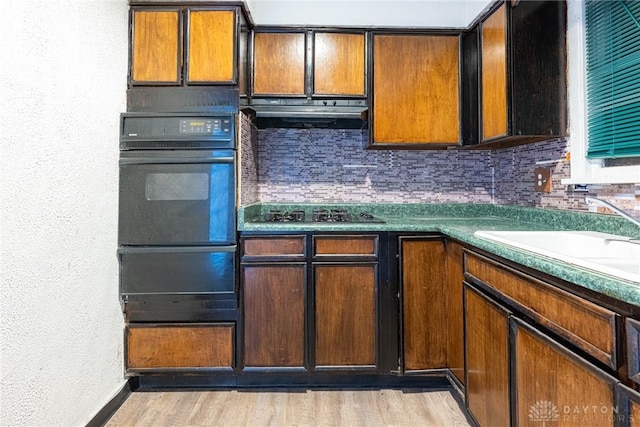 kitchen with sink, tasteful backsplash, black appliances, light wood-type flooring, and exhaust hood