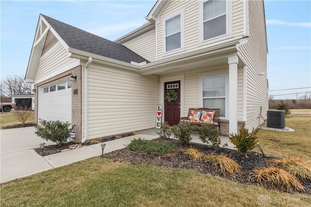 view of front of home with a garage, a porch, cooling unit, and a front lawn