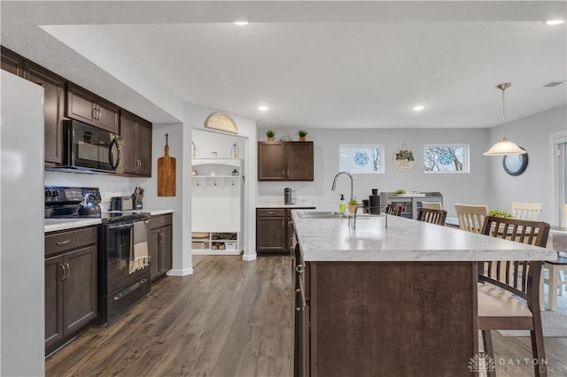 kitchen with sink, dark wood-type flooring, a kitchen island with sink, hanging light fixtures, and black appliances