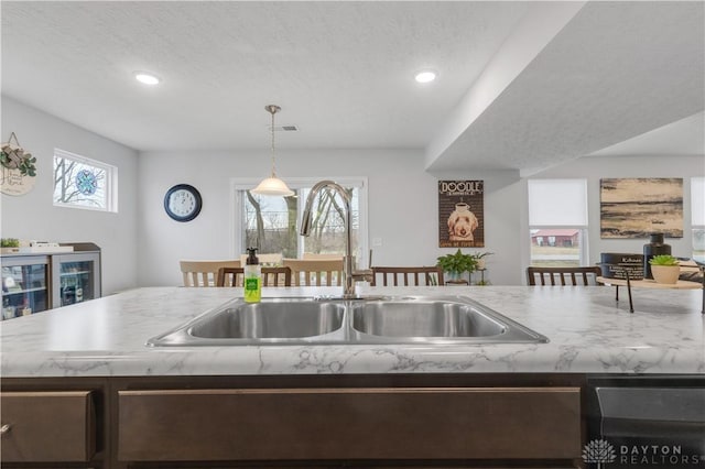 kitchen featuring sink, pendant lighting, beverage cooler, and a textured ceiling