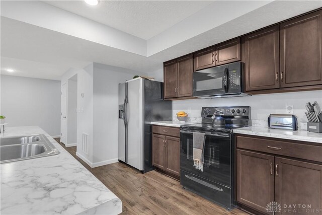 1605 Ashbury Ct, Franklin, OH 45005 - kitchen with wood finished floors, a sink, baseboards, dark brown cabinets, and black appliances