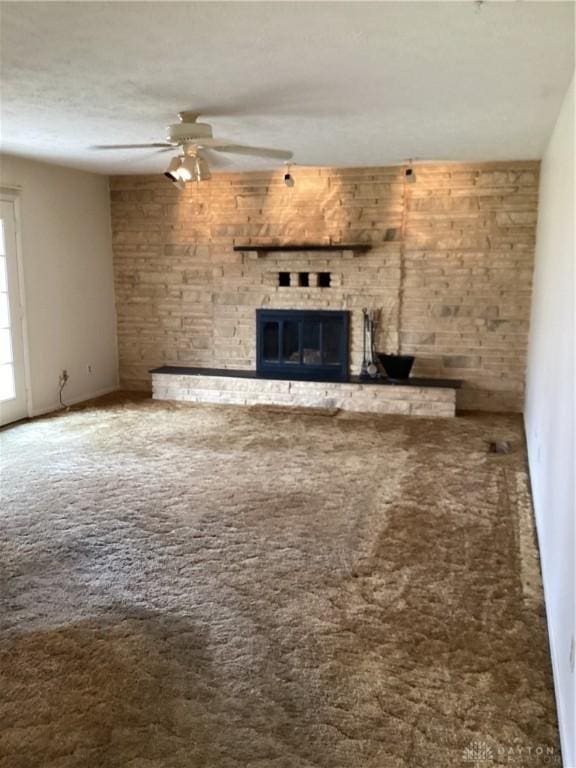 unfurnished living room featuring ceiling fan, a brick fireplace, and carpet