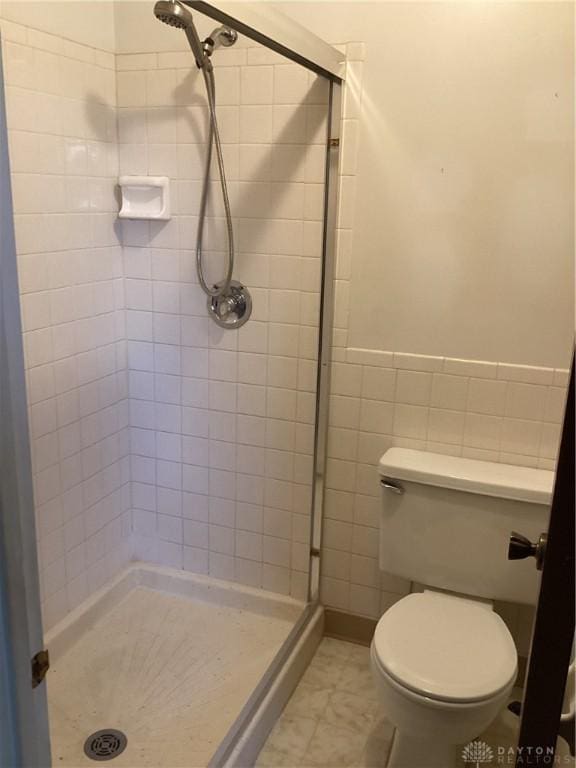 bathroom with toilet, tile walls, and a tile shower