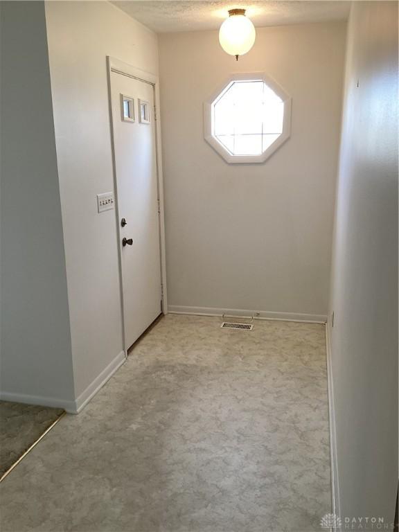 foyer entrance featuring light carpet and a textured ceiling