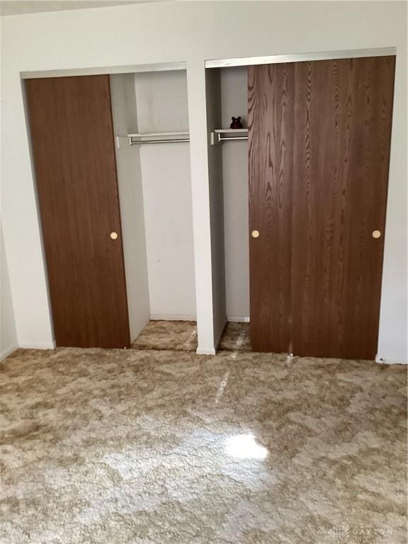 unfurnished bedroom featuring two closets and carpet flooring