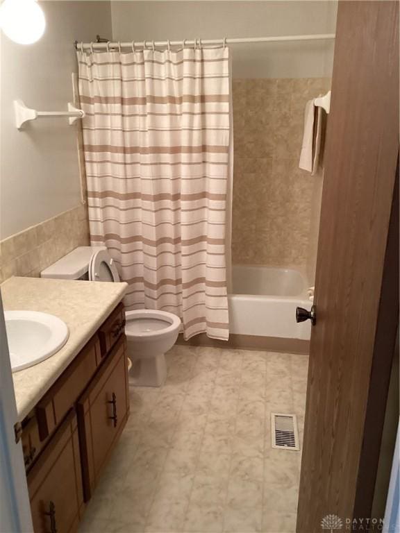 full bathroom with shower / tub combo with curtain, vanity, and toilet