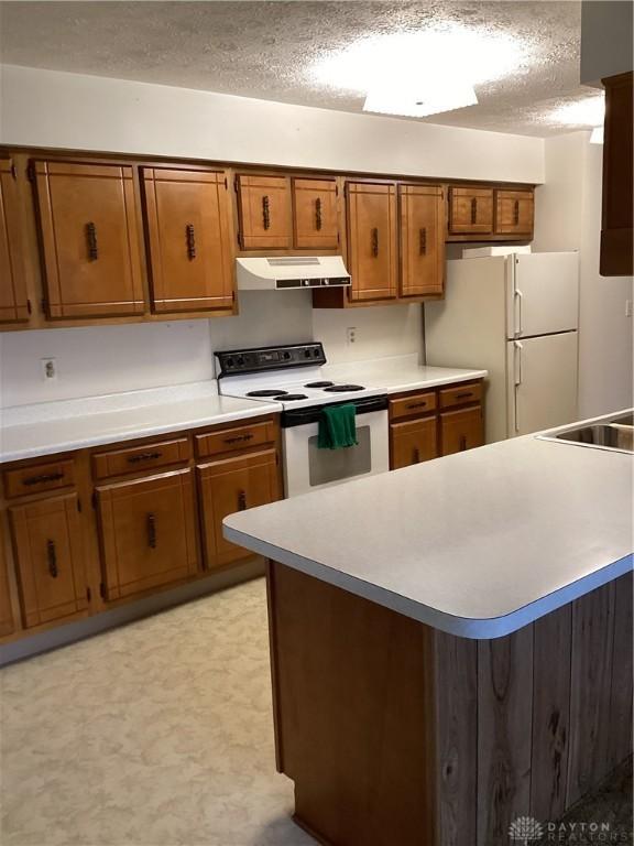 kitchen featuring sink, a textured ceiling, and white appliances