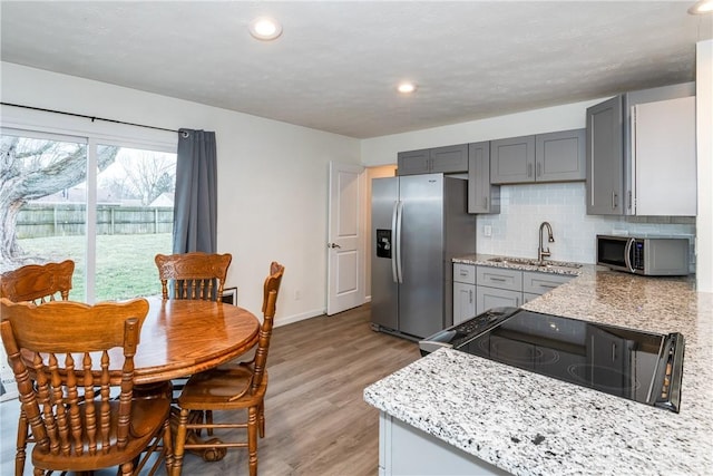 kitchen featuring sink, gray cabinets, stainless steel appliances, light hardwood / wood-style floors, and decorative backsplash