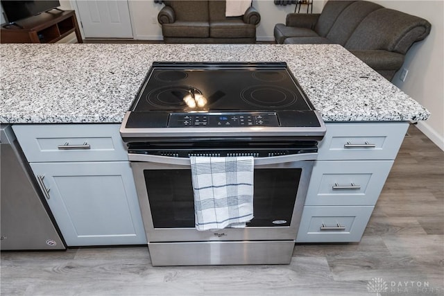 kitchen featuring stainless steel appliances, light stone countertops, and light hardwood / wood-style flooring