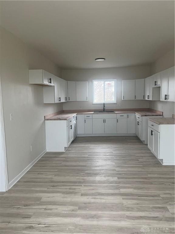 kitchen with light hardwood / wood-style floors, sink, and white cabinets