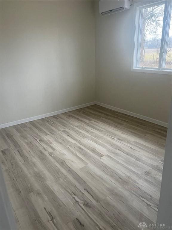 unfurnished room featuring an AC wall unit and light wood-type flooring