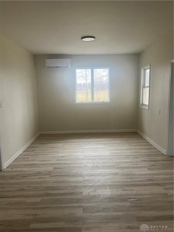 spare room featuring hardwood / wood-style flooring and a wall mounted air conditioner