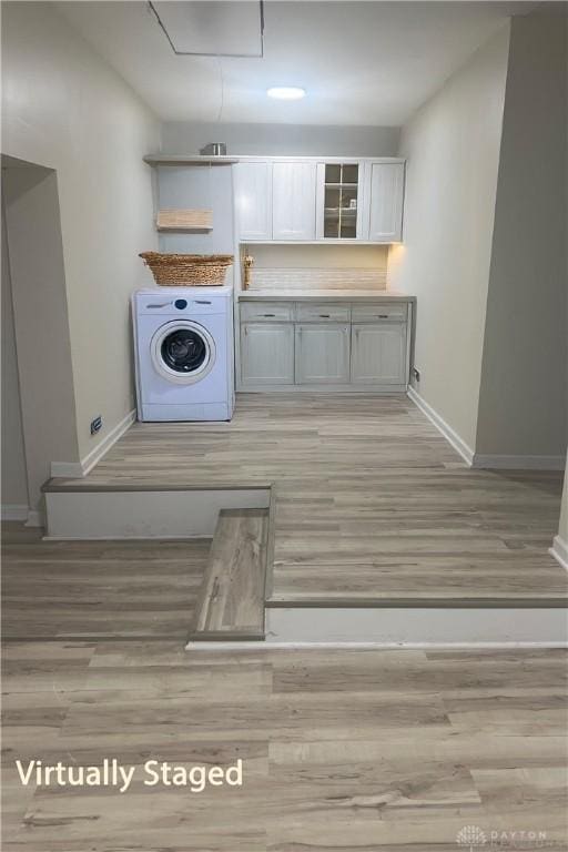 washroom with washer / dryer, light hardwood / wood-style floors, and cabinets