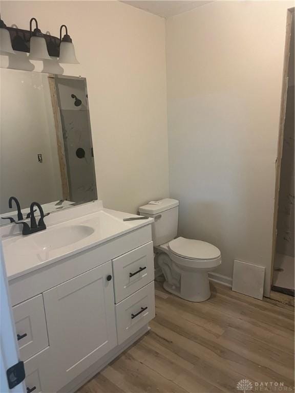 bathroom featuring hardwood / wood-style flooring, vanity, walk in shower, and toilet