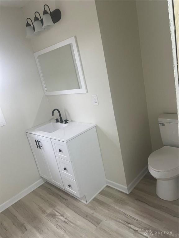 bathroom featuring wood-type flooring, vanity, and toilet